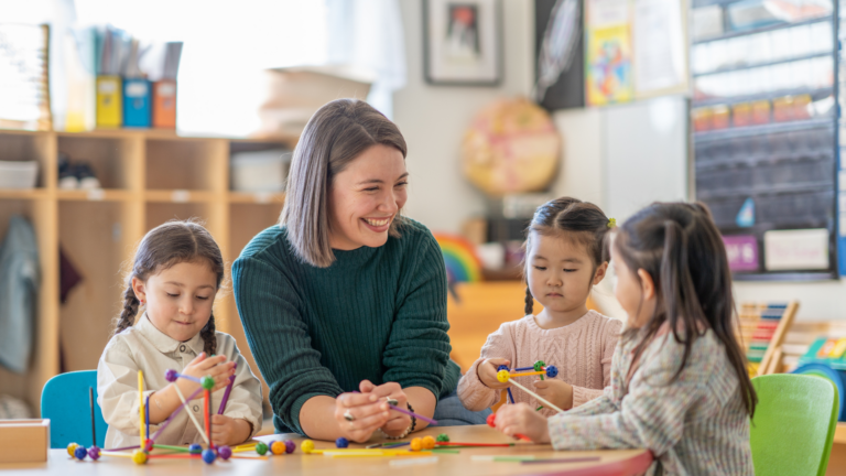 Three children playing at a table with an adult